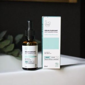 Sérum purifiant anti-imperfections Clémence & Vivien, flacon pipette brun posé sur mousse et fleurs, soin visage bio au zinc et acides naturels